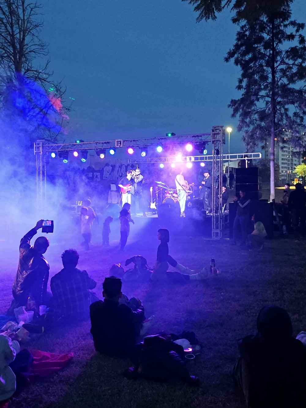 Público frente a un escenario de recital de noche, con haces de luz y humo saliendo del rig montado por Top Dj Group